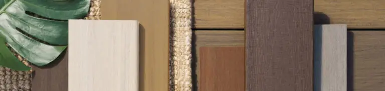 Rectangular wood and laminate samples in neutral tones are arranged on a woven mat next to a monstera leaf, inspiring your next DIY deck materials selection or deck install, all set against a wooden surface.