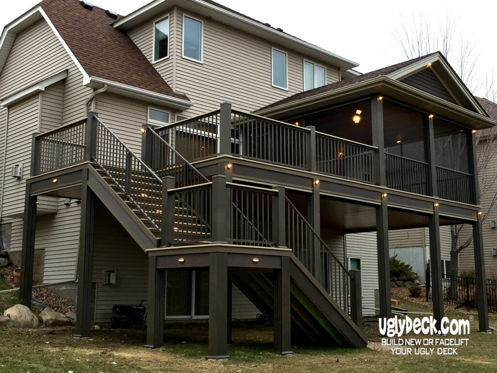 A two-story house with a large, elevated deck features stairs, railings, and built-in lights. This custom deck install includes a screened-in section and dark wood materials. The uglydeck.com logo appears in the lower right corner.